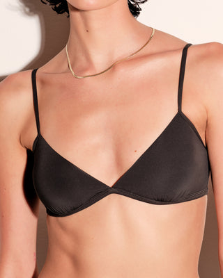 Black bra worn by a woman with a neutral background