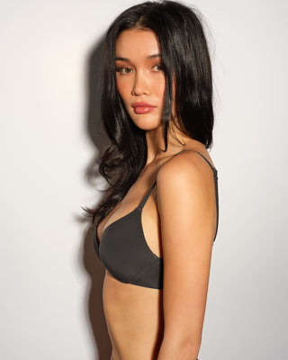 Woman wearing a black pushup bra against a plain background